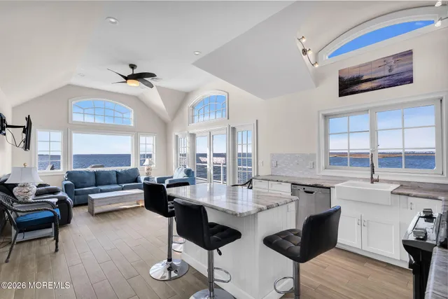 a living room with stainless steel appliances kitchen island granite countertop furniture and a wooden floor