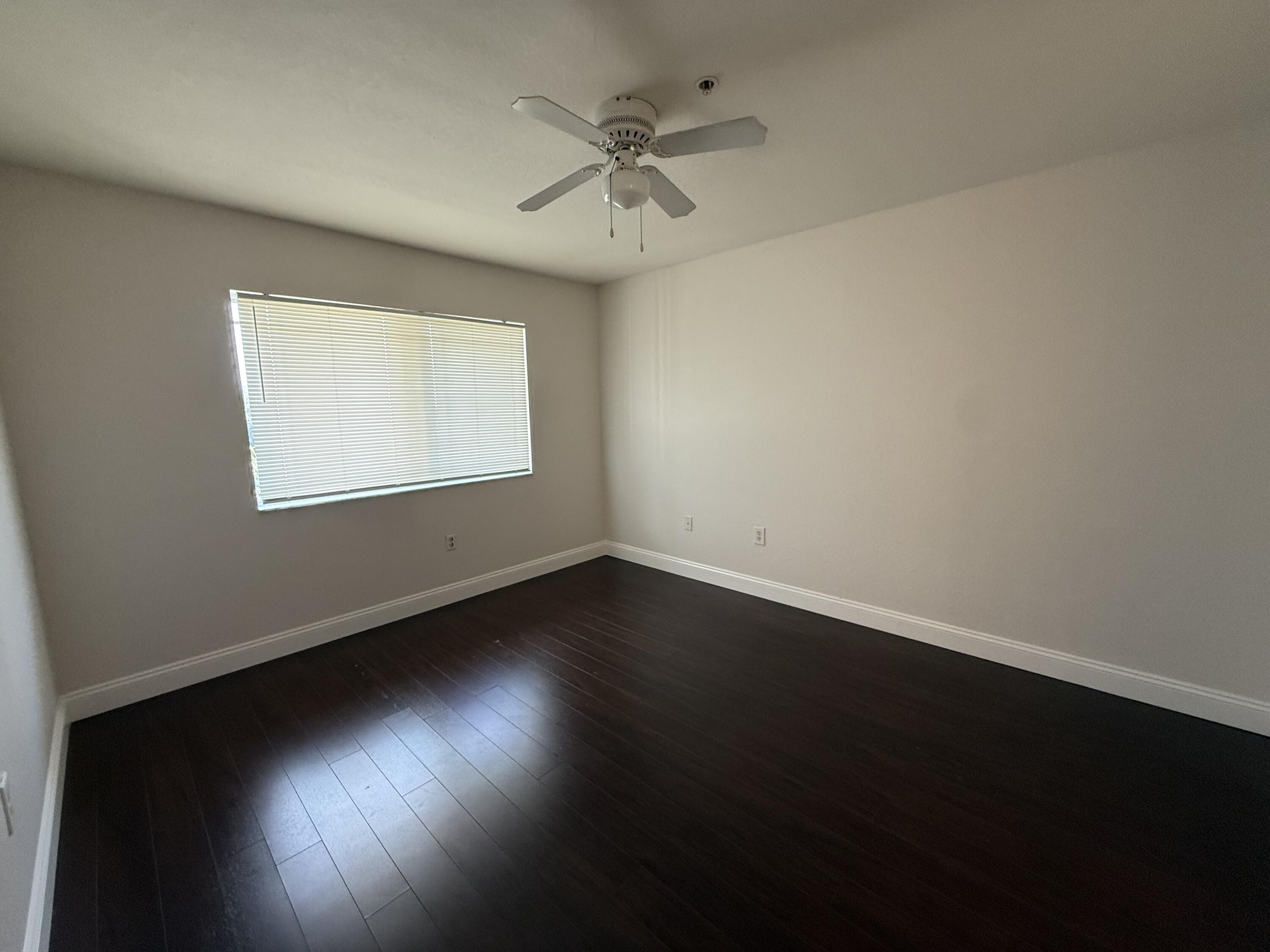 171 Southwest Palm Drive, Unit 303 Port St. Lucie, FL 34986 - Photo 3 of 9 an empty room with wooden floor and windows