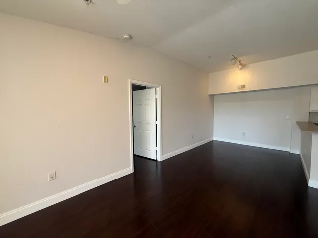 a view of an empty room with wooden floor and a window