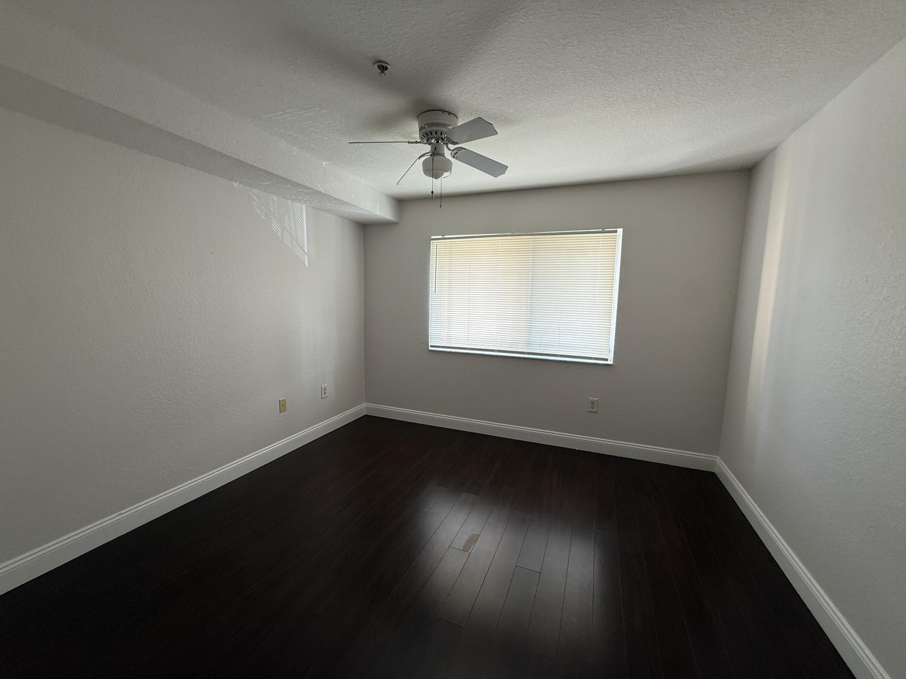 171 Southwest Palm Drive, Unit 303 Port St. Lucie, FL 34986 - Photo 7 of 9 a view of an empty room with wooden floor and a window