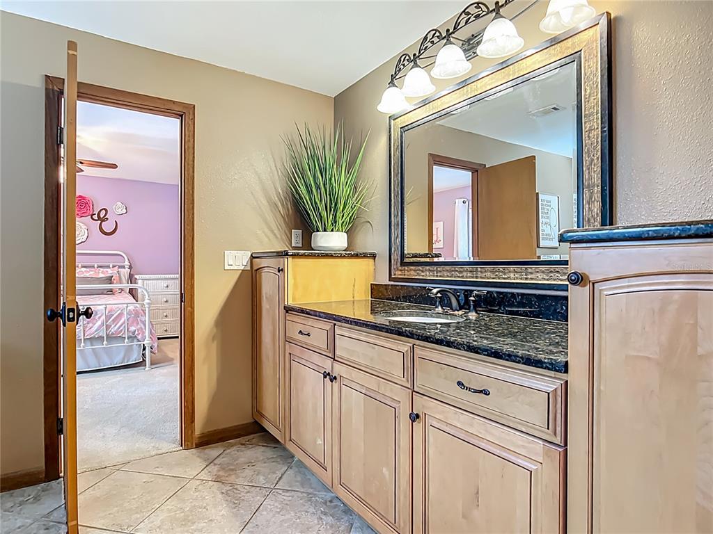 4661 Southwest 7th Avenue Road Ocala, FL 34471 - Photo 56 of 94 a en suite bathroom with a granite countertop sink and a mirror