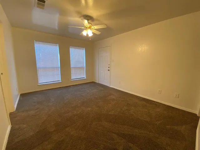 a view of an empty room with a chandelier fan