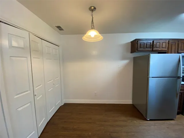 a view of a kitchen with refrigerator and wooden floor