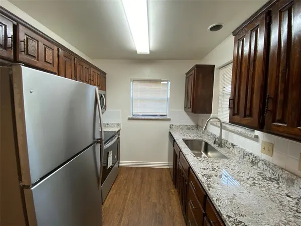 a kitchen with granite countertop stainless steel appliances a refrigerator and a sink