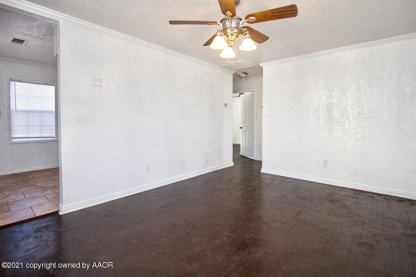 4431 Bowie Street Amarillo, TX 79110 - Photo 3 of 13 an empty room with wooden floor fan and windows