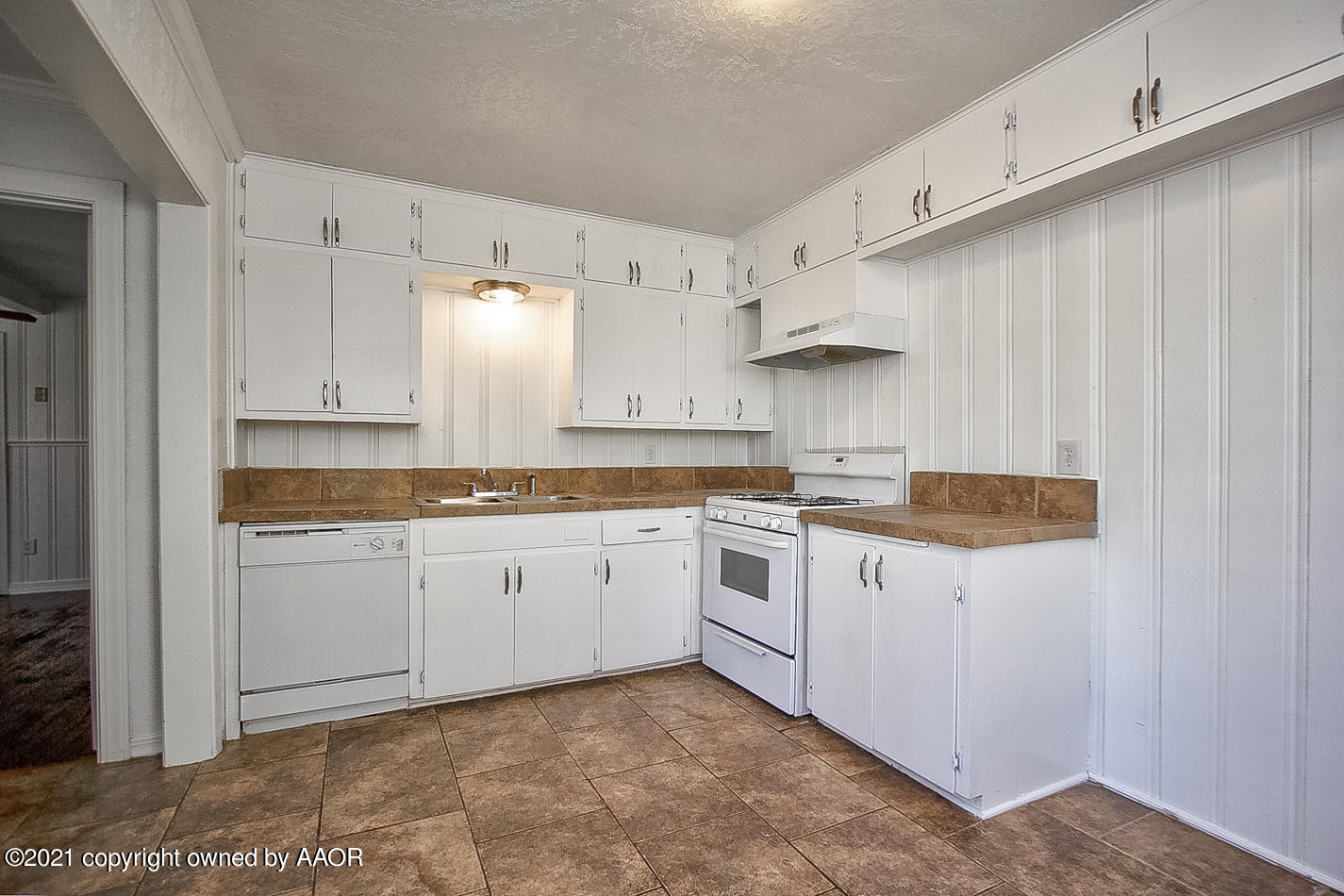 4431 Bowie Street Amarillo, TX 79110 - Photo 4 of 13 a kitchen with granite countertop white cabinets and white appliances