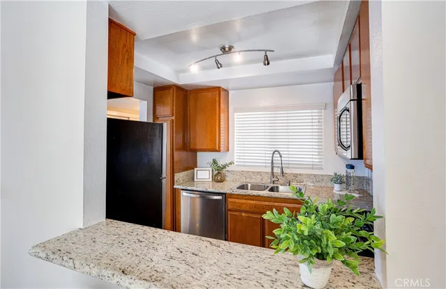 a kitchen with stainless steel appliances kitchen island granite countertop a sink and a refrigerator