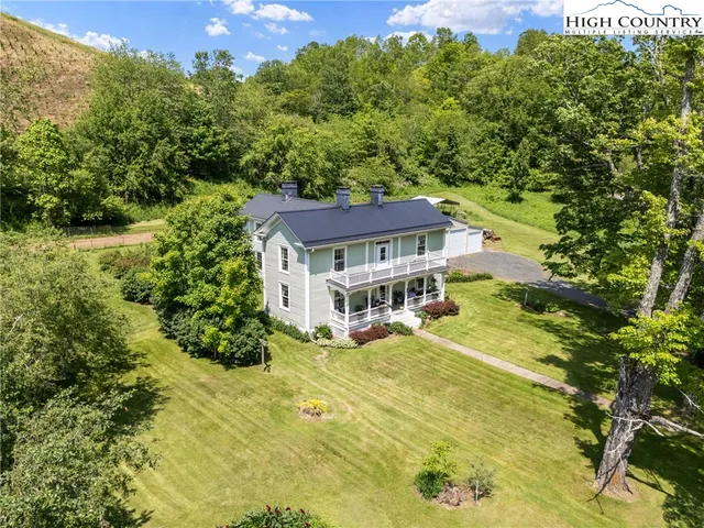 a view of a house with a big yard and large trees