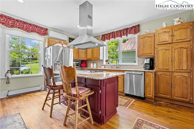 a kitchen with stainless steel appliances granite countertop a table chairs and a large window