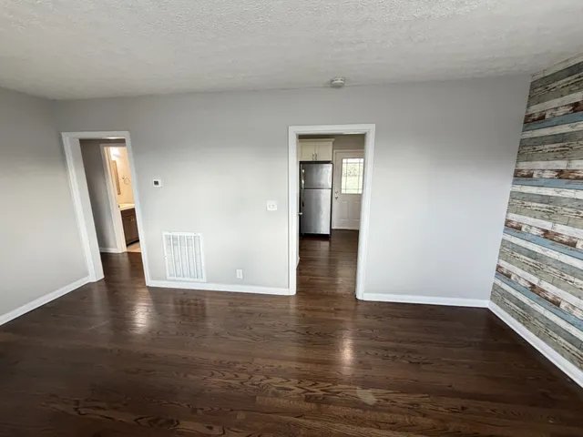 a view of empty room with wooden floor and window
