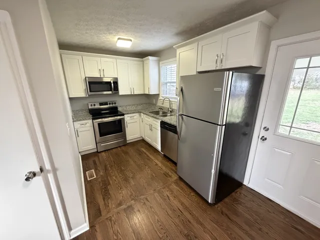 a kitchen with granite countertop a sink stove and microwave