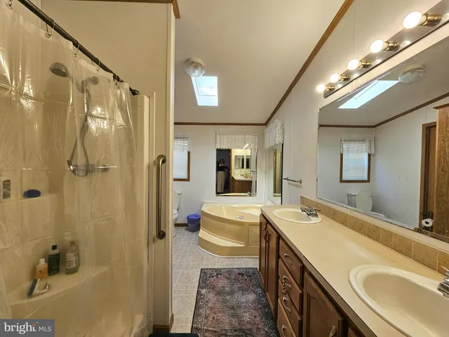a spacious bathroom with a double vanity sink a mirror and a shower