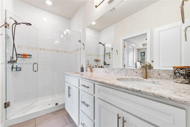 a bathroom with a granite countertop sink mirror and shower