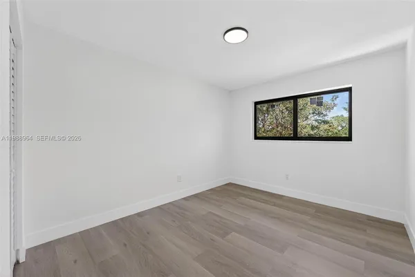 an empty room with wooden floor and window