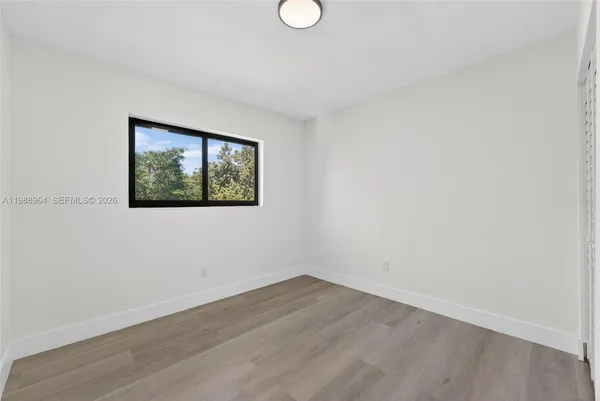 an empty room with wooden floor and window