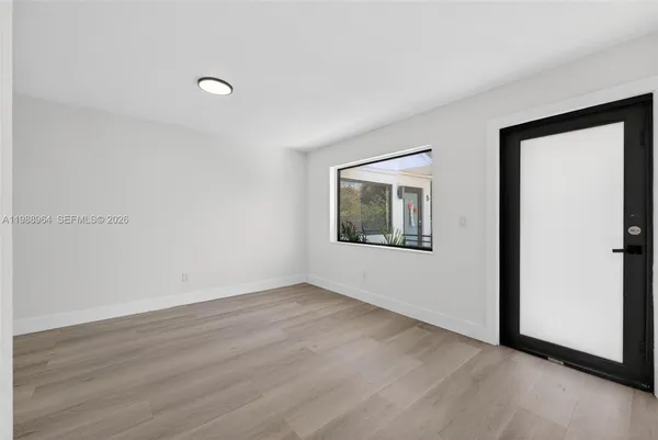a view of an empty room with wooden floor and a window