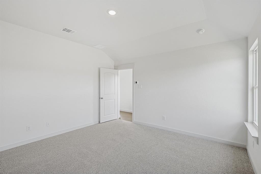 1714 Glacial Beech Place Forney, TX 75126 - Photo 11 of 25 Carpeted spare room with vaulted ceiling and baseboards
