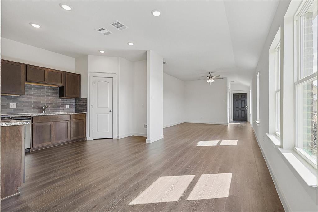1714 Glacial Beech Place Forney, TX 75126 - Photo 7 of 25 Kitchen featuring dark wood-type flooring, light stone counters, backsplash, dark brown cabinets, and ceiling fan