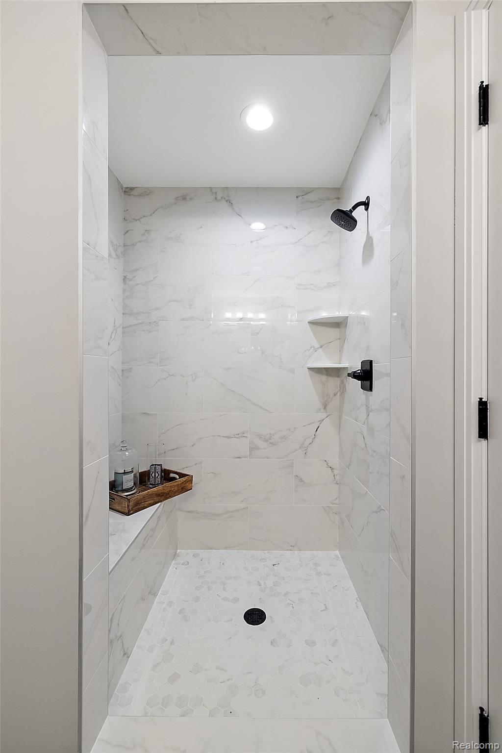8267 Sandi Lane Romeo, MI 48065 - Photo 43 of 46 Tiled shower enclosure featuring a built-in bench, two corner shelves, black finish shower fixtures, and a recessed ceiling light