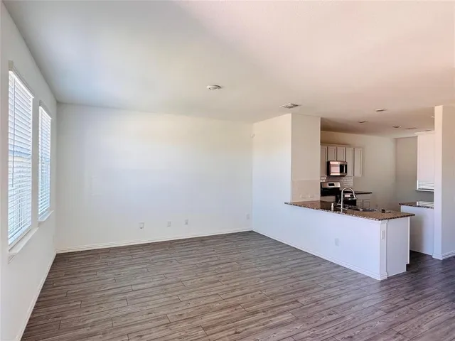 a view of a kitchen with wooden floor and white cabinets