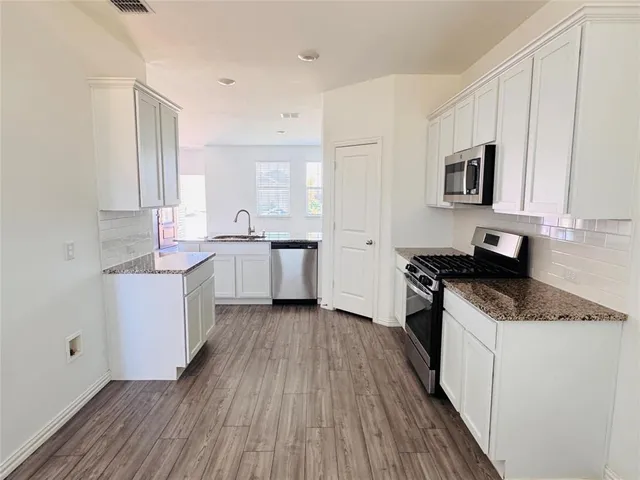 a kitchen with a sink stove top oven and cabinets