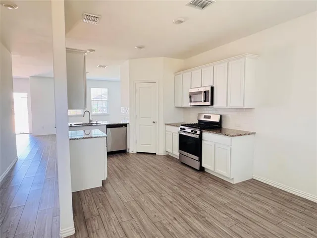 a kitchen with granite countertop white cabinets and stainless steel appliances