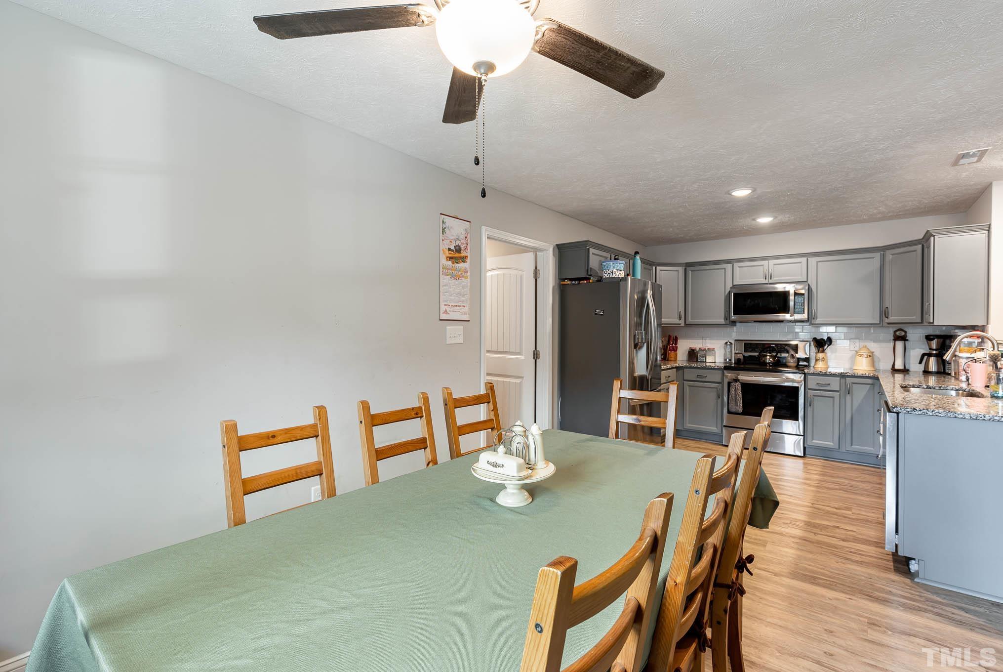 6551 Faircloth Bridge Road Stedman, NC 28391 - Photo 11 of 30 a dining room with stainless steel appliances kitchen island granite countertop a dining table chairs and a refrigerator