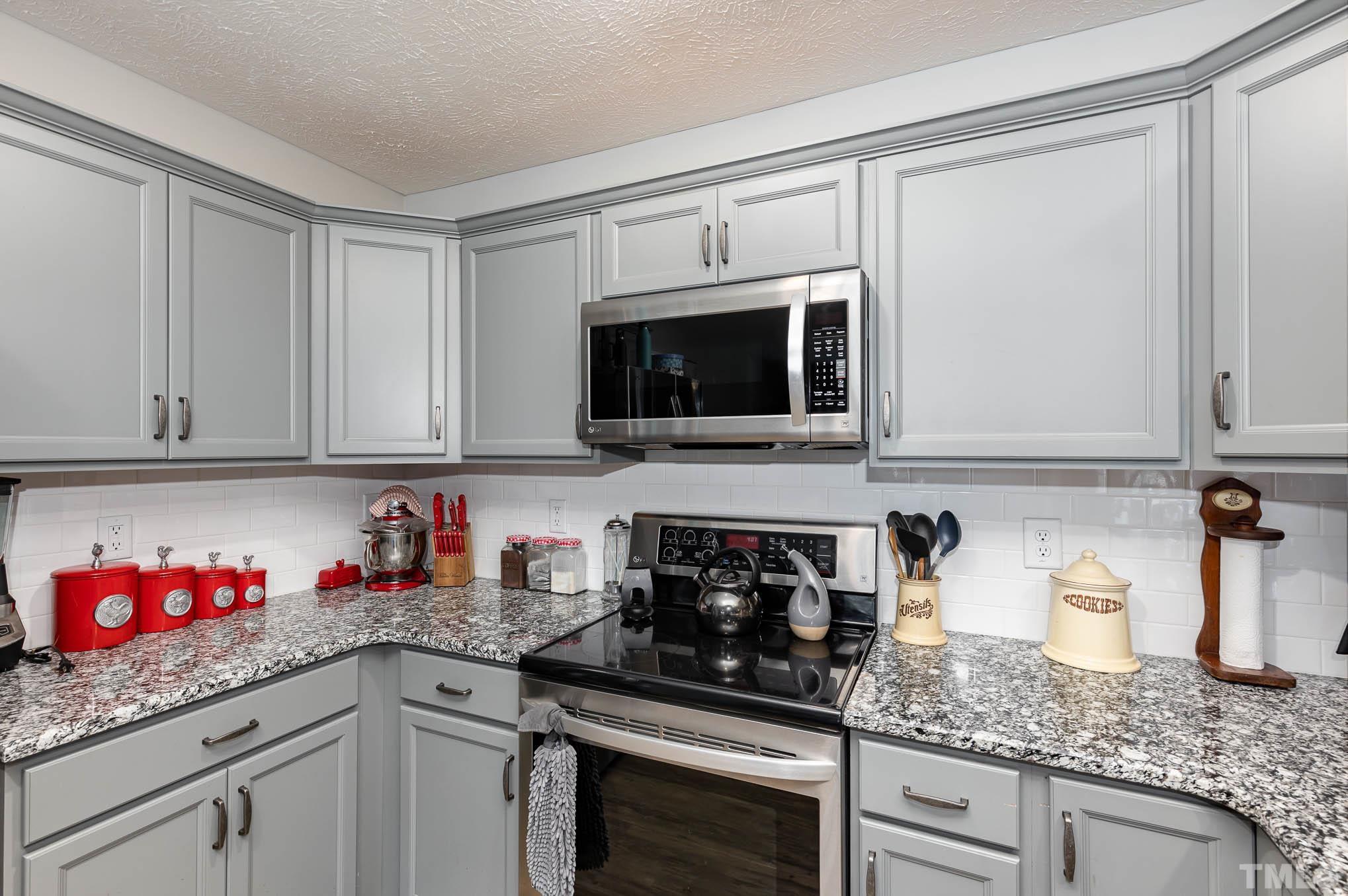 6551 Faircloth Bridge Road Stedman, NC 28391 - Photo 13 of 30 a kitchen with granite countertop white cabinets and a stove