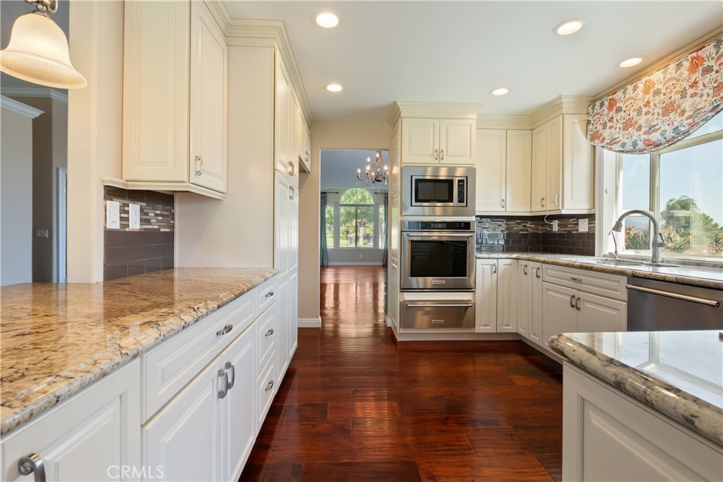 6717 Mission Grove Parkway North Riverside, CA 92506 - Photo 17 of 58 a kitchen with kitchen island granite countertop a stove top oven a sink a counter space and cabinets