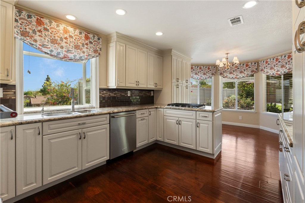 6717 Mission Grove Parkway North Riverside, CA 92506 - Photo 18 of 58 a kitchen with granite countertop white cabinets and white appliances with wooden floor