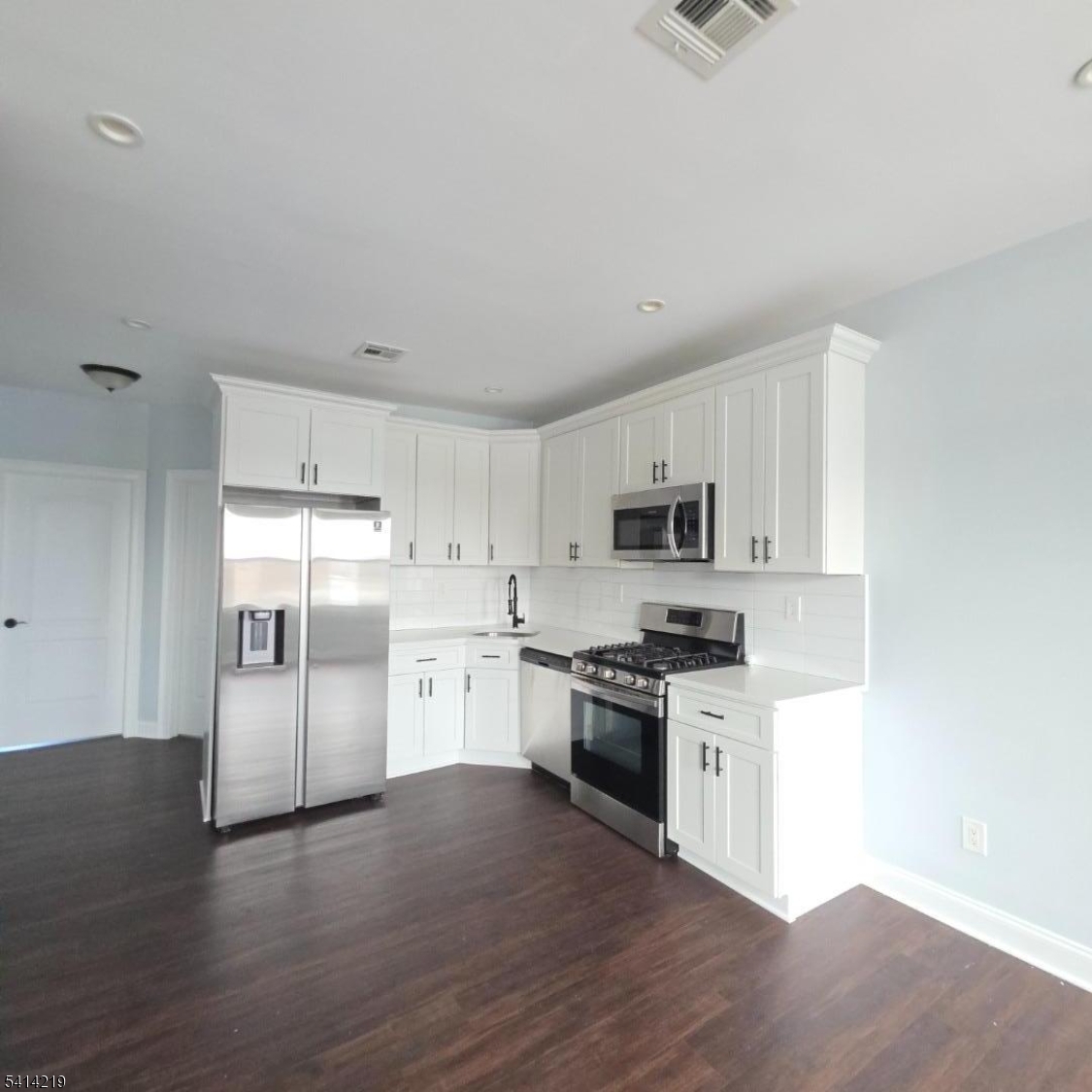 322 Rutherford Boulevard Clifton, NJ 07014 - Photo 7 of 8 a kitchen with stainless steel appliances granite countertop a stove top oven a refrigerator a sink and dishwasher with wooden floor