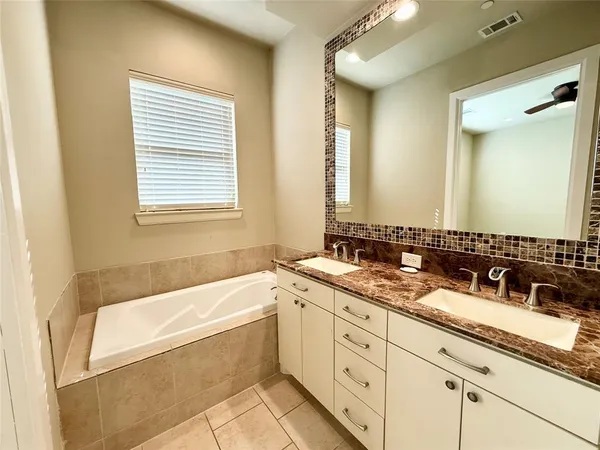 a bathroom with a granite countertop tub sink and mirror