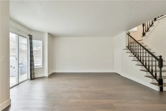 a view of an empty room with wooden floor and stairs