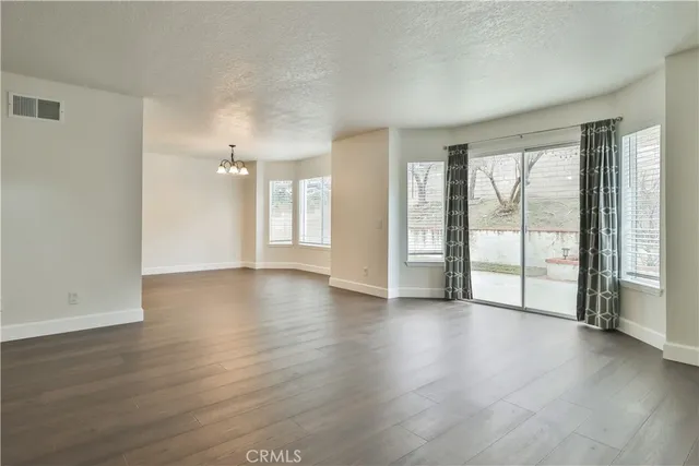 an empty room with wooden floor and windows with curtains