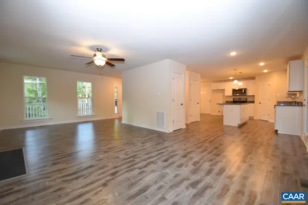 a view of an empty room with kitchen and window