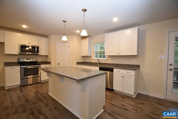 a kitchen with kitchen island granite countertop a sink a counter space appliances and cabinets