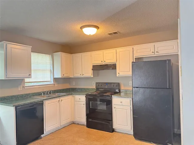 a kitchen with a refrigerator sink stove and cabinets