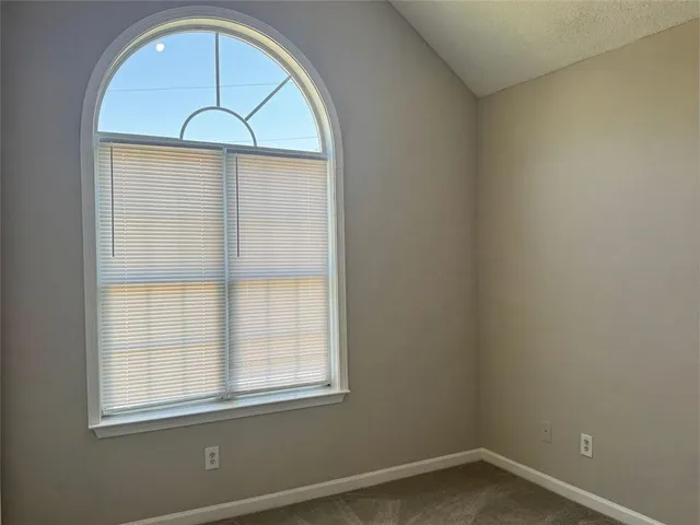 an empty room with wooden floor fan and window