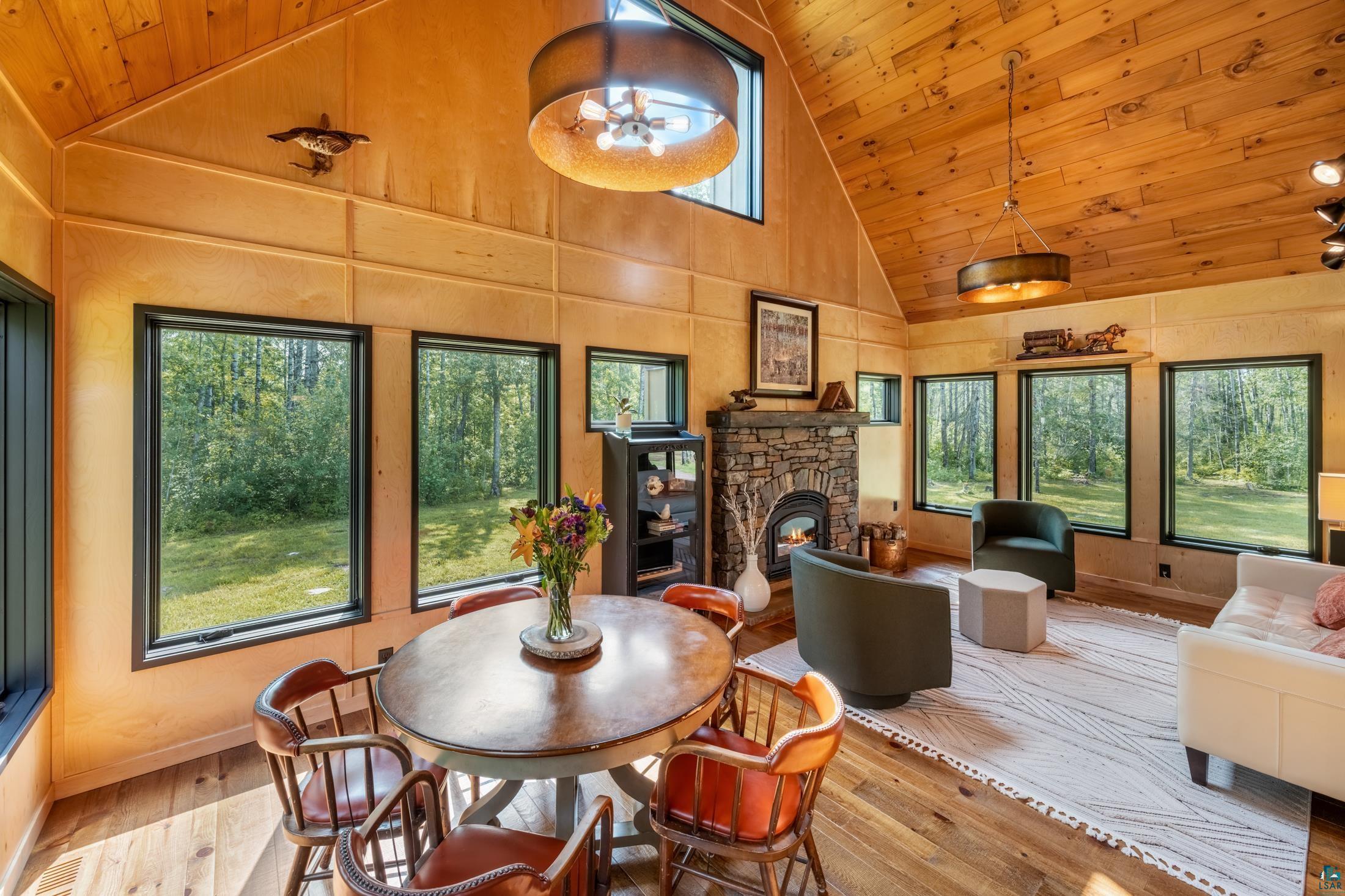 3778 East County Road Barnum, MN 55707 - Photo 31 of 52 Vaulted wood-paneled ceiling, wood-finish flooring, multiple fixed windows, a stone-clad fireplace, and a built-in shelving unit