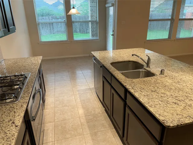 a kitchen with kitchen island granite countertop a stove a sink and a microwave