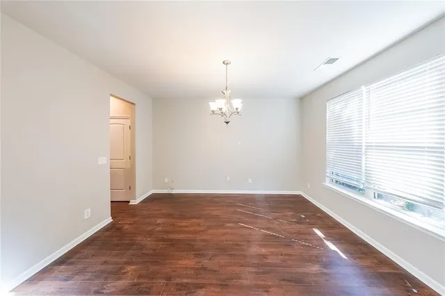 an empty room with wooden floor chandelier fan and windows