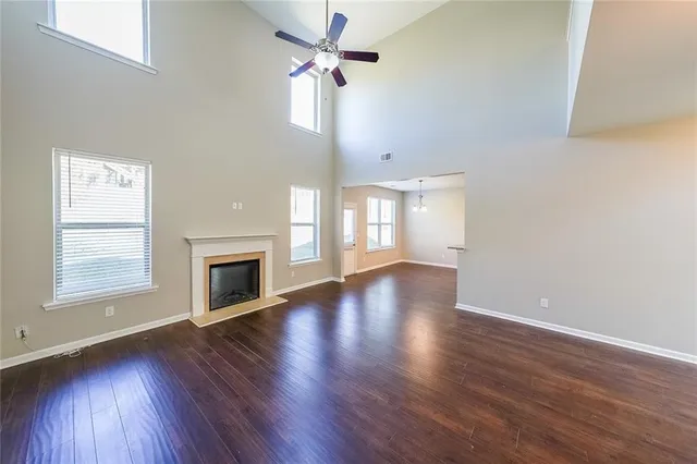 an empty room with wooden floor fireplace and windows