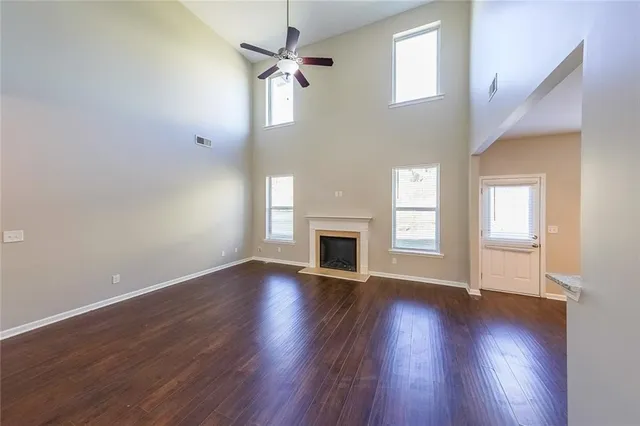 an empty room with wooden floor fireplace and windows