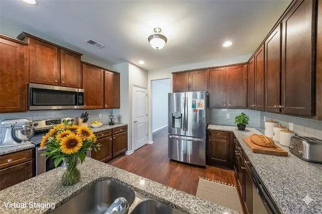 a kitchen with stainless steel appliances granite countertop a refrigerator a stove and a sink with wooden floor