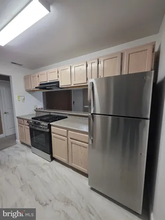 a kitchen with granite countertop a refrigerator and a stove top oven