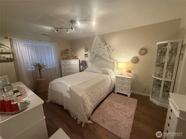 a bedroom with a bed and a table with wooden floor