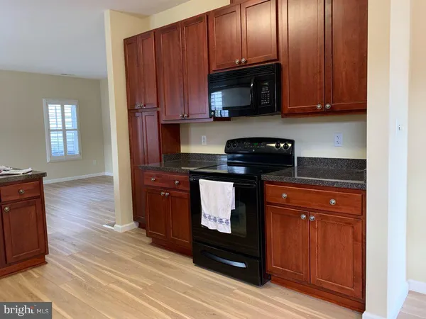 a kitchen with granite countertop wooden cabinets and a stove top oven