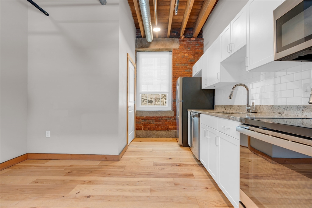 58 13th Street, Unit T105 Boston, MA 02129 - Photo 3 of 15 a kitchen with granite countertop a stove and a refrigerator