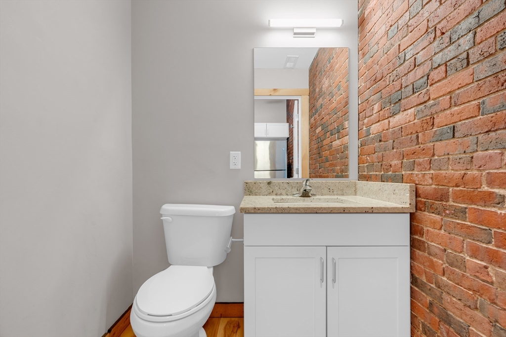 58 13th Street, Unit T105 Boston, MA 02129 - Photo 4 of 15 a bathroom with a granite countertop toilet a sink and a mirror