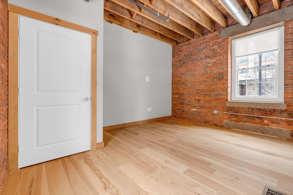 58 13th Street, Unit T105 Boston, MA 02129 - Photo 6 of 15 a view of an empty room with wooden floor and a window